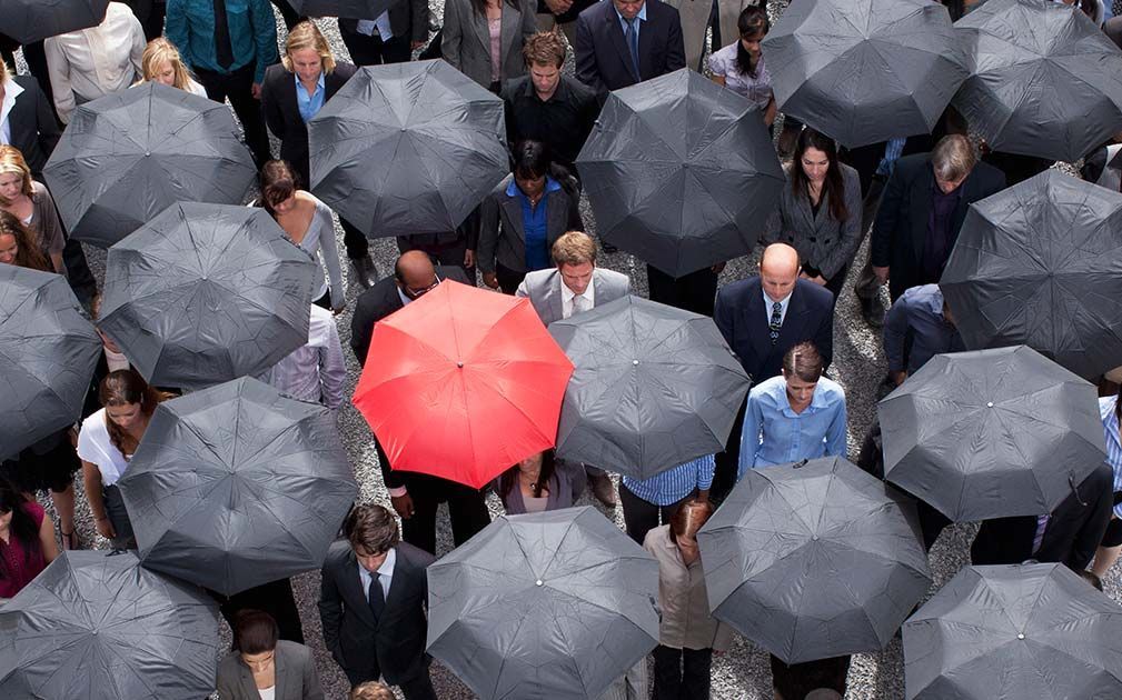 a man holding a red umbrella stands in a crowd of people