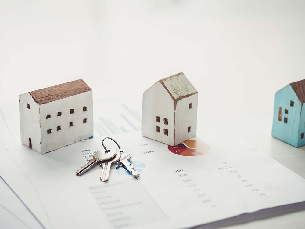 three wooden houses and keys on top of a book