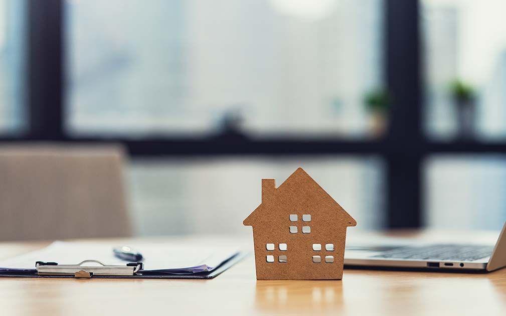 a small wooden house sits on a desk next to a laptop