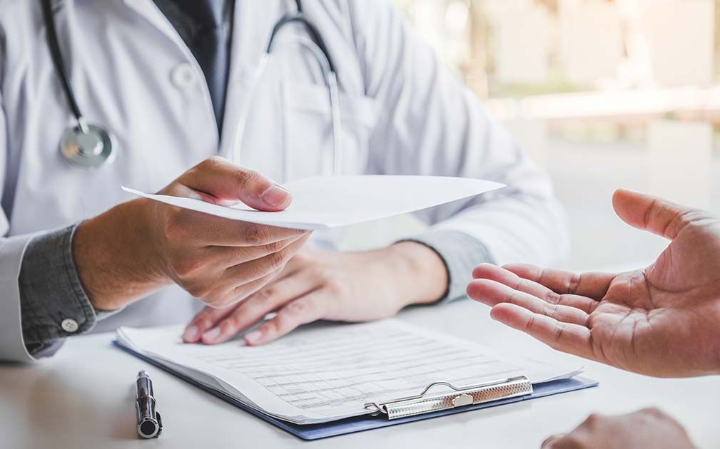 a doctor is handing a patient a piece of paper