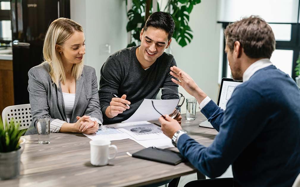 a man and woman are sitting at a table looking at papers