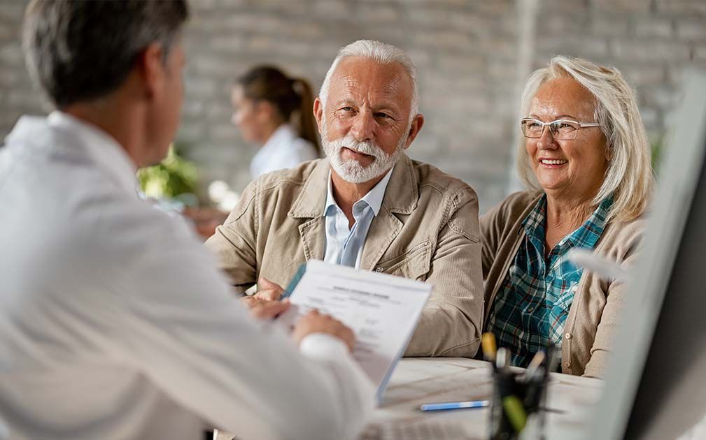 a man and woman are sitting at a table talking to a doctor .