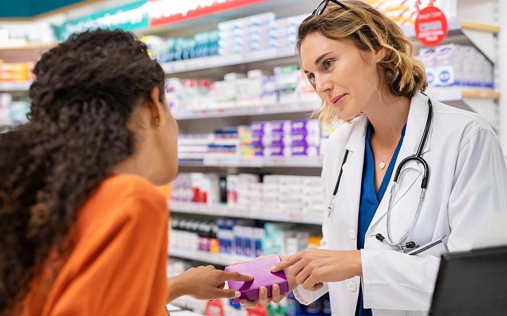 a female pharmacist is talking to a woman in a pharmacy