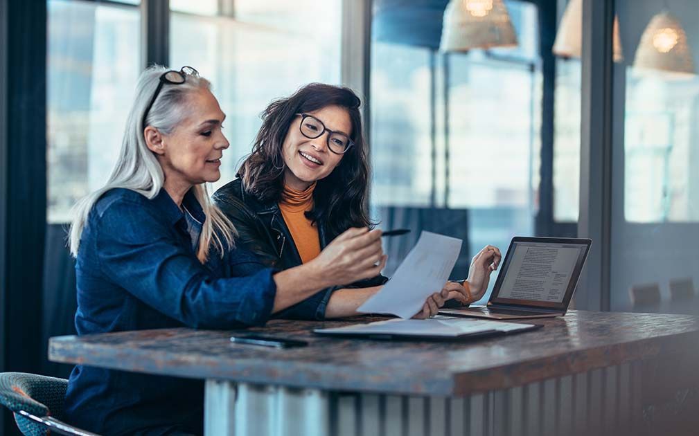 two women are sitting at a table looking at a piece of paper