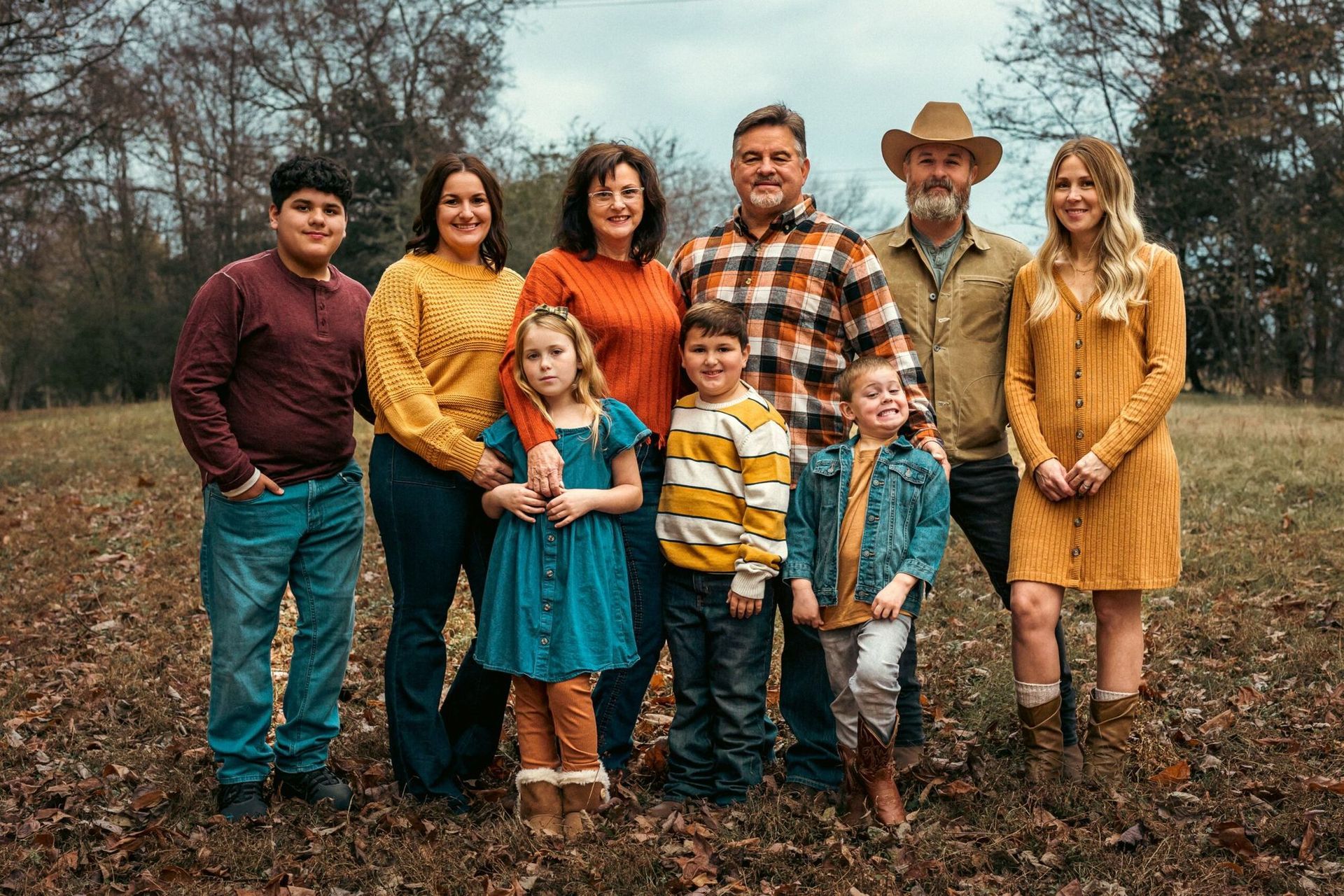 A large family is posing for a picture in a field.