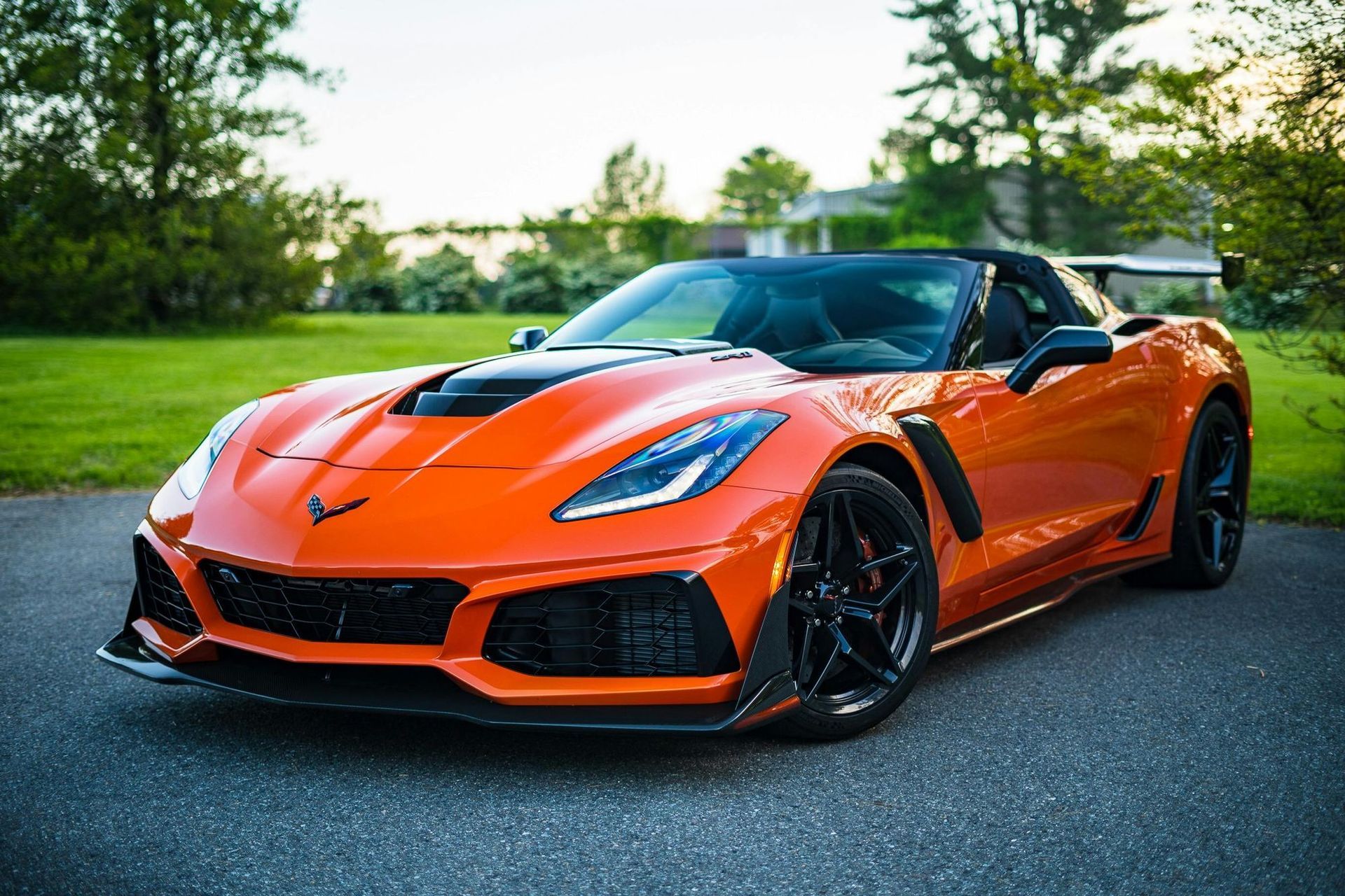 An orange corvette zr1 is parked on the side of the road.