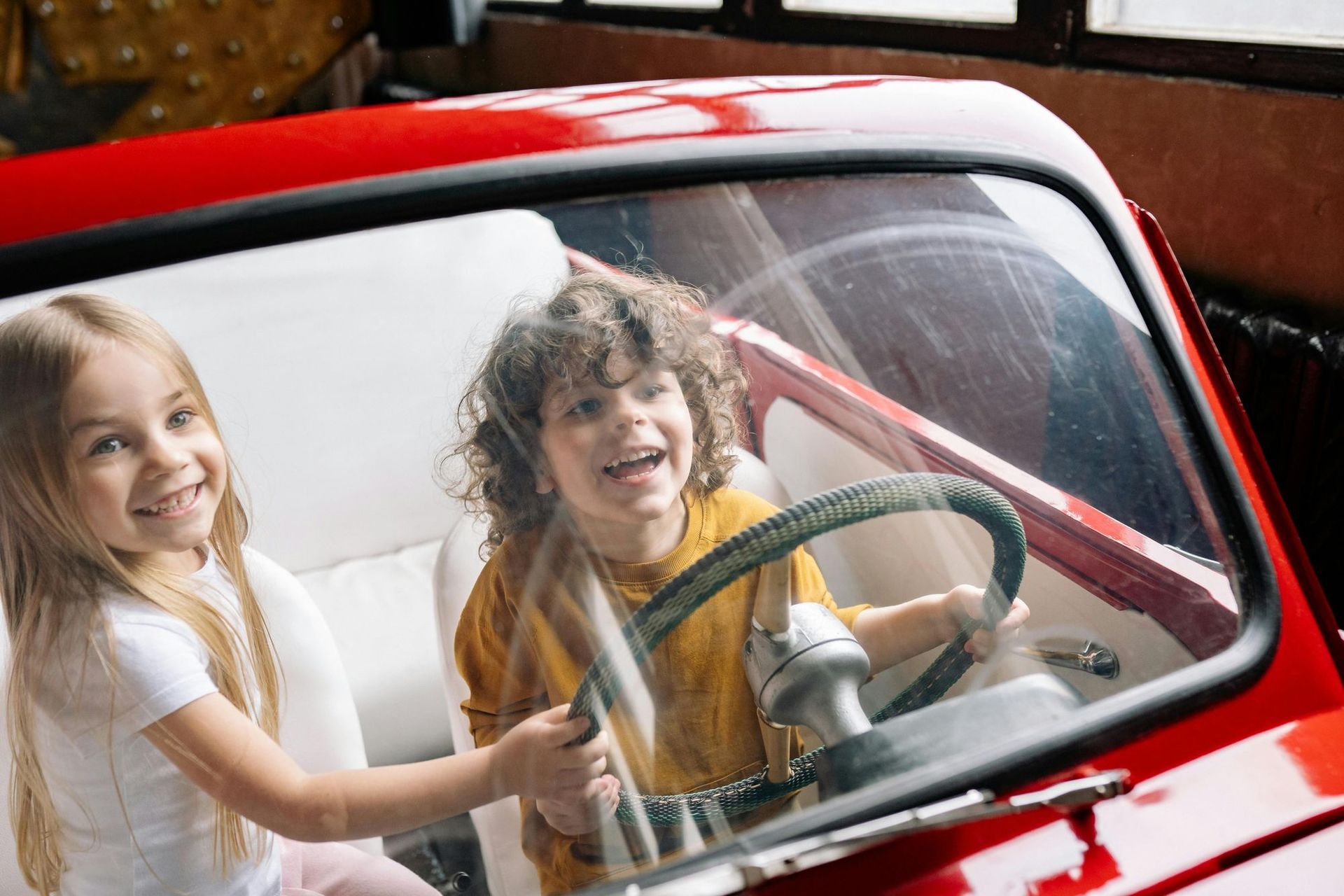 A boy and a girl are sitting in a red car.