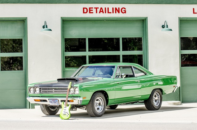 A green car is parked in front of a garage that says detailing.