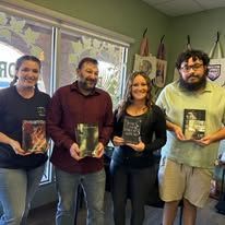 Four people holding awards inside a store. Two women and two men smiling.