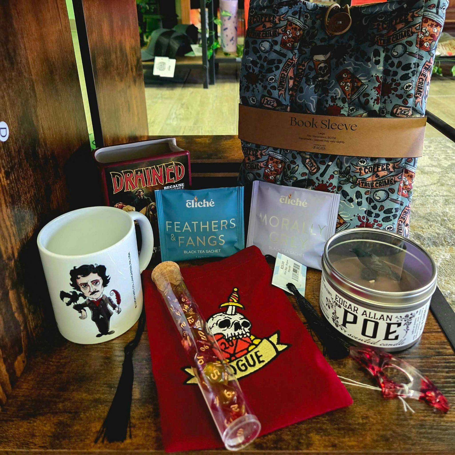 Gift set with a mug, books, candle, candy, and red pouch on a wooden surface