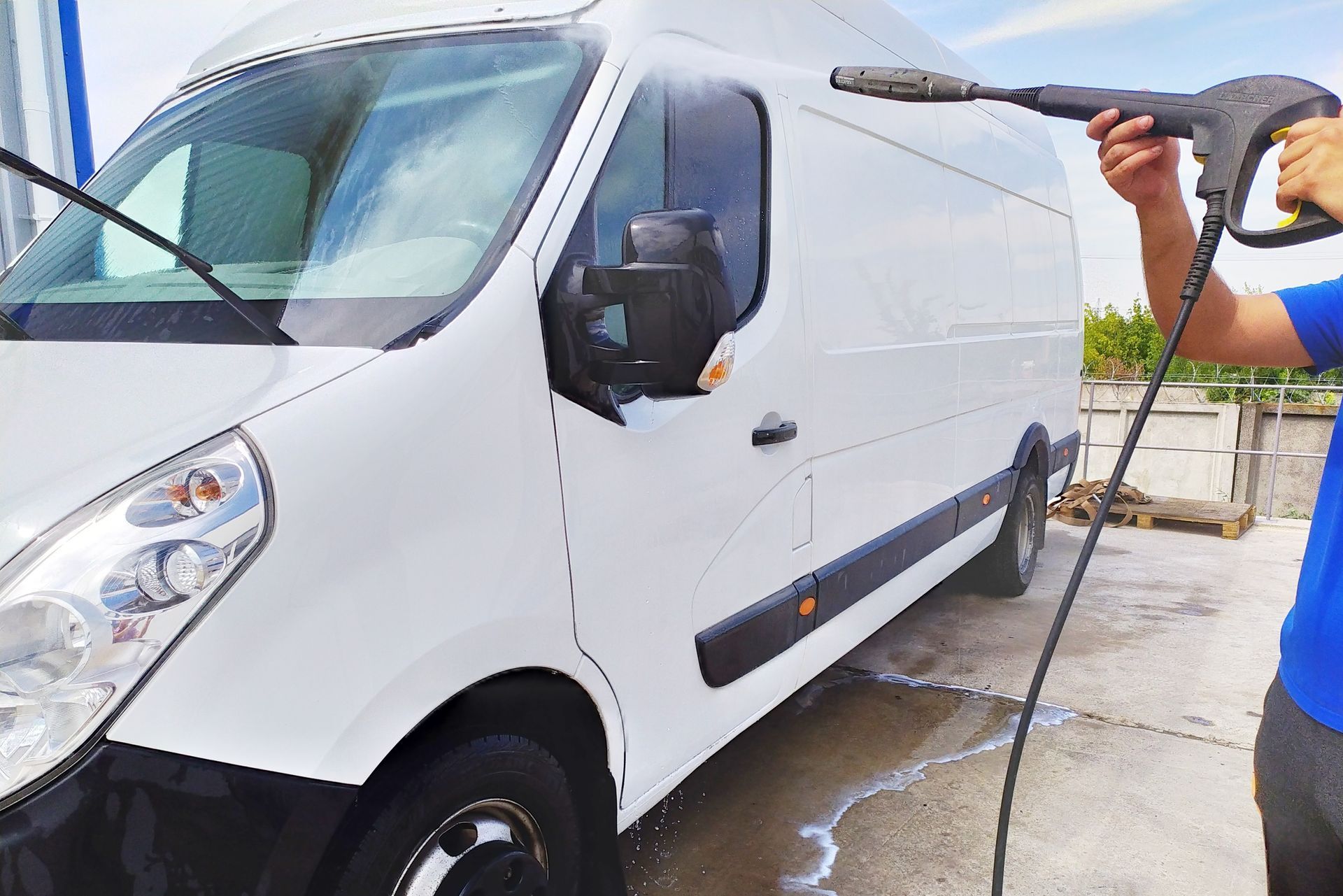 Technician pressure washing a commercial box truck in a fleet yard near Asheville
