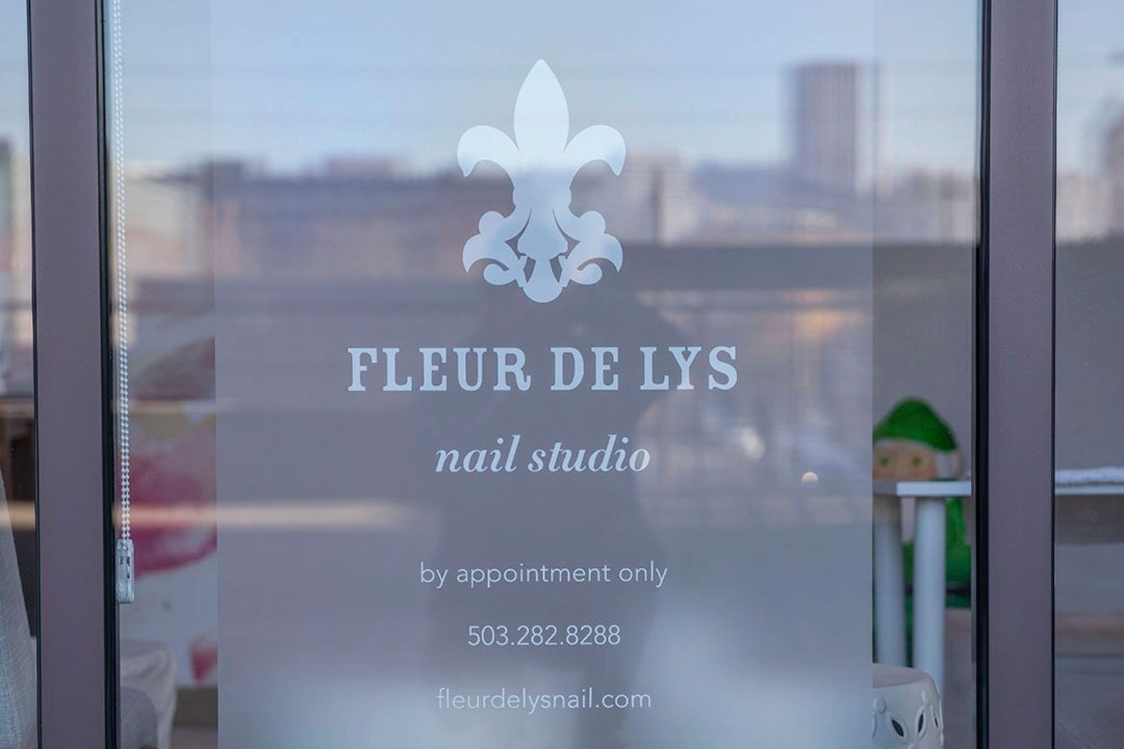 Fleur de Lys nail studio window sign with white logo and text on frosted glass