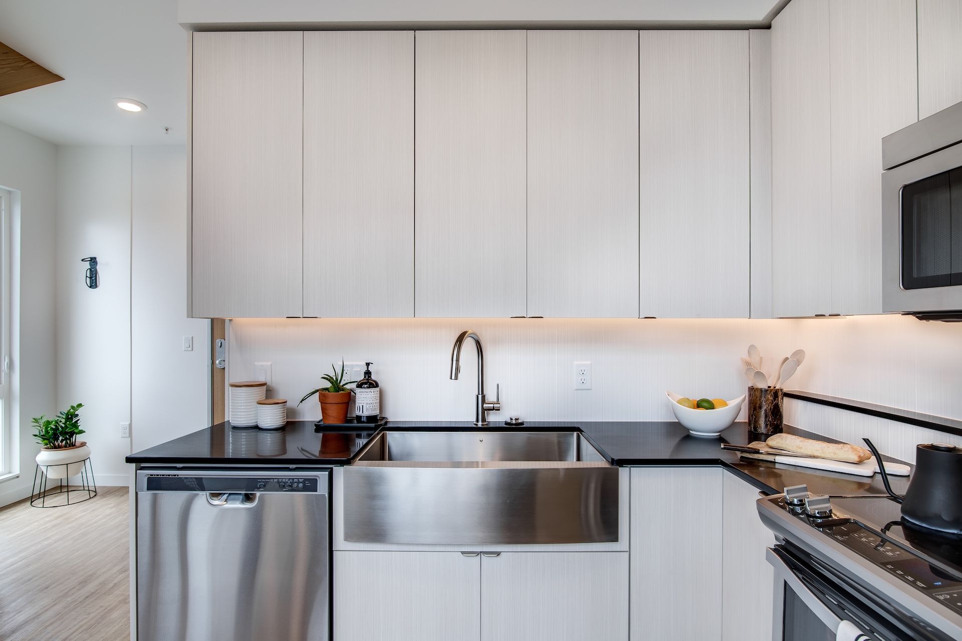 Modern kitchen with stainless steel sink, dishwasher, stove, and light wood cabinets