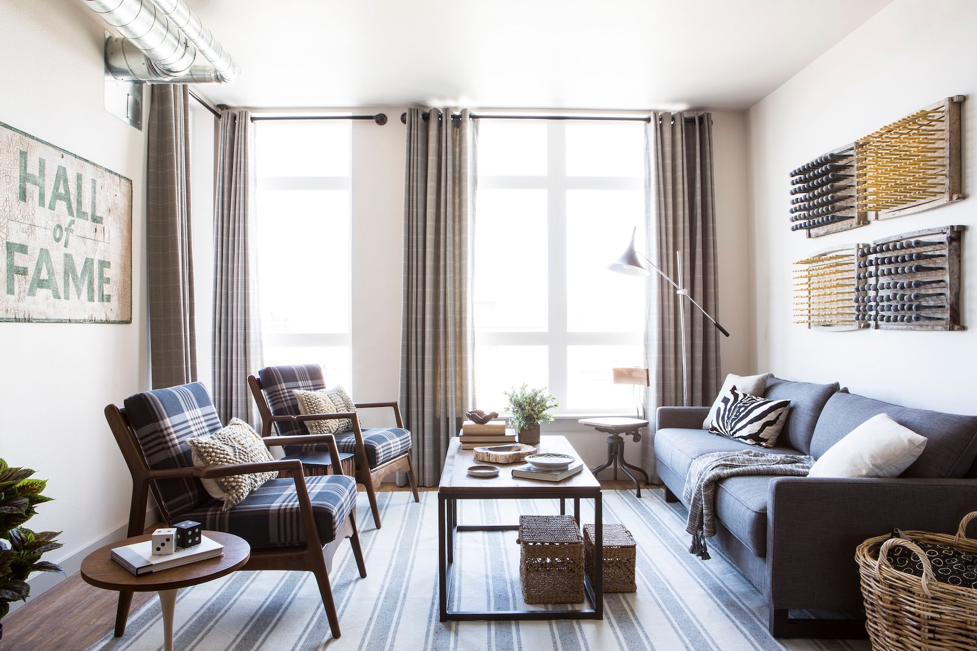 Bright living room with gray sofa, armchairs, coffee table, and large sunlit windows
