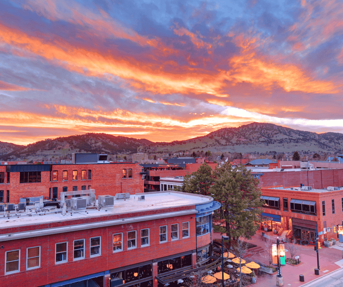 An aerial view of a city at sunset with mountains in the background.