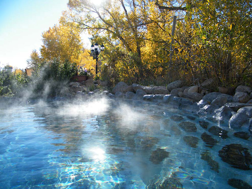 A pool of water with steam coming out of it and trees in the background in Cottonwood Hot Springs Colorado