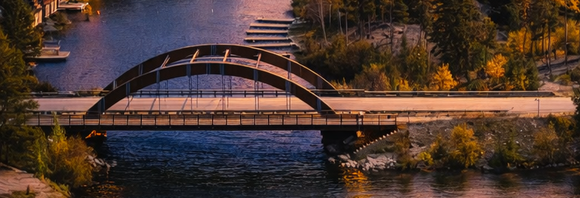 Arched bridge over a river at sunset, surrounded by autumn trees and reflected in the water