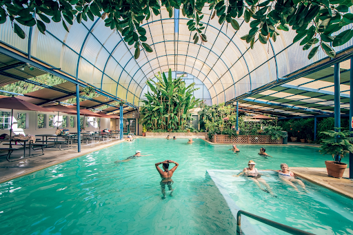 A group of people are swimming in a large indoor swimming pool in Indian Hot Springs Colorado 