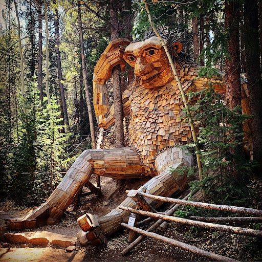 A large wooden statue of a troll in the woods