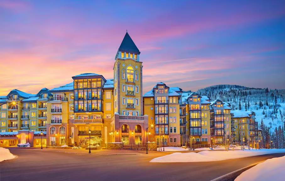 The Ritz Carlton building in Vail with a tower on top of it is surrounded by snow.