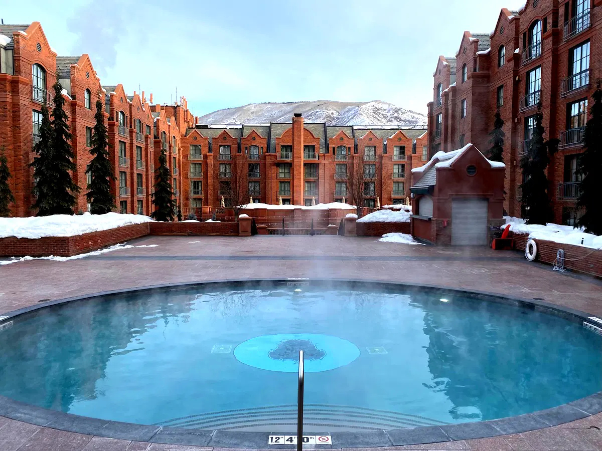 The St. Regis in Aspen with a large swimming pool in front of a brick building.