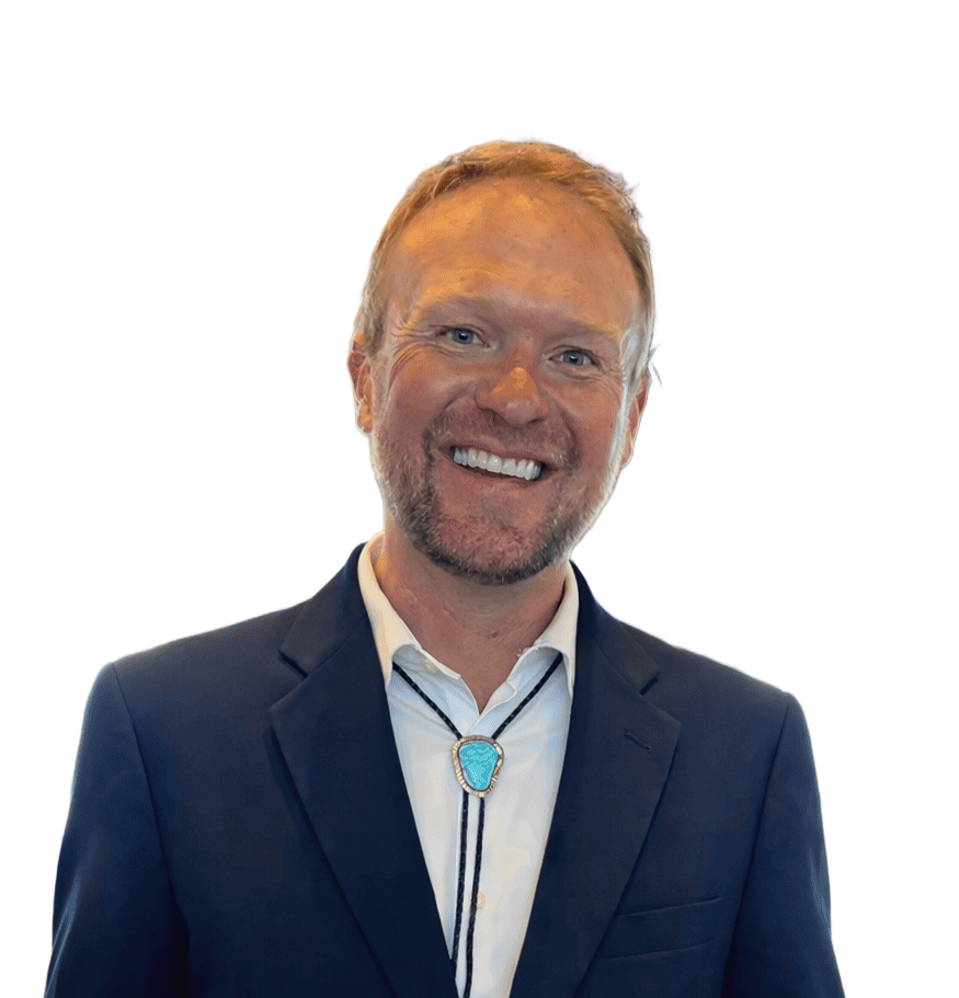 A smiling person wearing a blue blazer, white collared shirt, and a turquoise bolo tie, set against a white background.