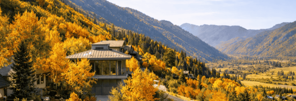 Mountain valley with a temple, golden autumn trees, and distant blue peaks under a clear sky