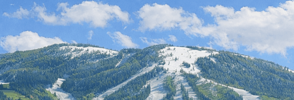 Snow-covered mountain slopes under a blue sky with scattered clouds