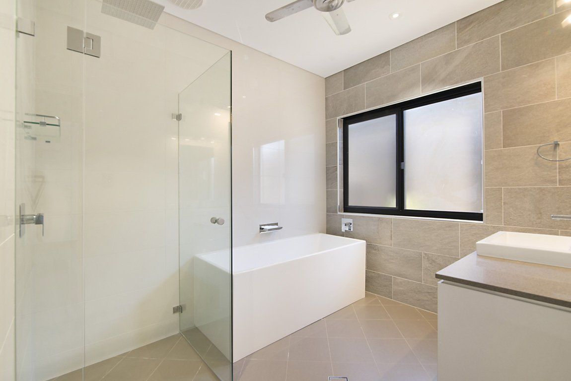 A Bathroom With a Bathtub, Sink, Shower and Window — Precision Shower Screens & Wardrobes In Virginia, NT
