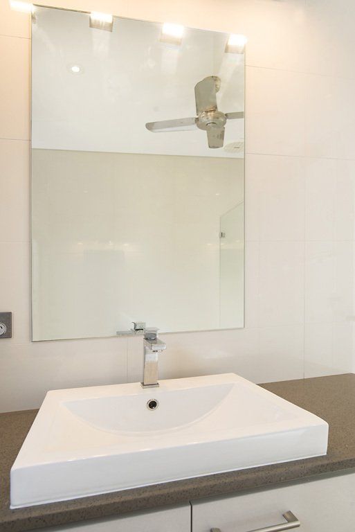 A Bathroom With a Sink, Mirror and Ceiling Fan — Precision Shower Screens & Wardrobes In Darwin, NT