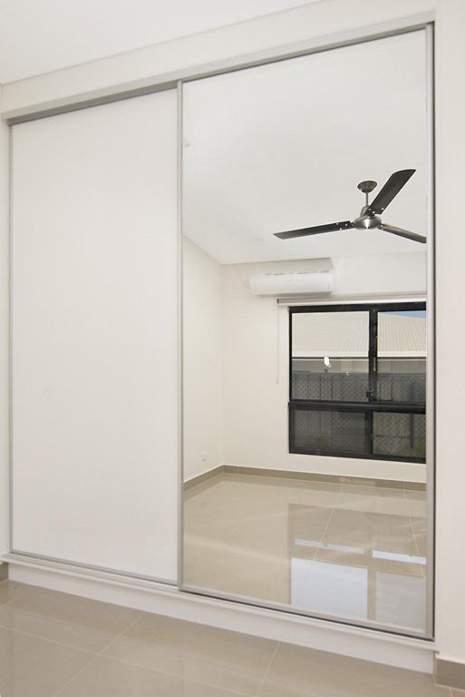 A Bedroom With a Ceiling Fan and a Large Mirror on the Wall — Precision Shower Screens & Wardrobes In Yarrawonga, NT