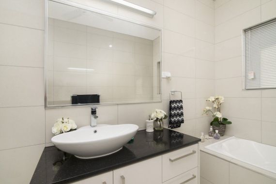 A Bathroom With a Sink, Mirror and Bathtub — Precision Shower Screens & Wardrobes In Yarrawonga, NT