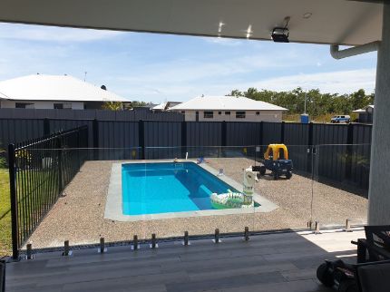 A Large Swimming Pool is Surrounded by a Fence and a Deck — Precision Shower Screens & Wardrobes In Yarrawonga, NT