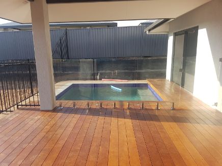 A Wooden Deck With a Swimming Pool in the Background — Precision Shower Screens & Wardrobes In Katherine, NT