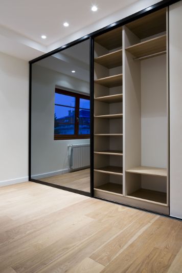 An Empty Room With a Sliding Glass Door and Shelves — Precision Shower Screens & Wardrobes In Yarrawonga, NT