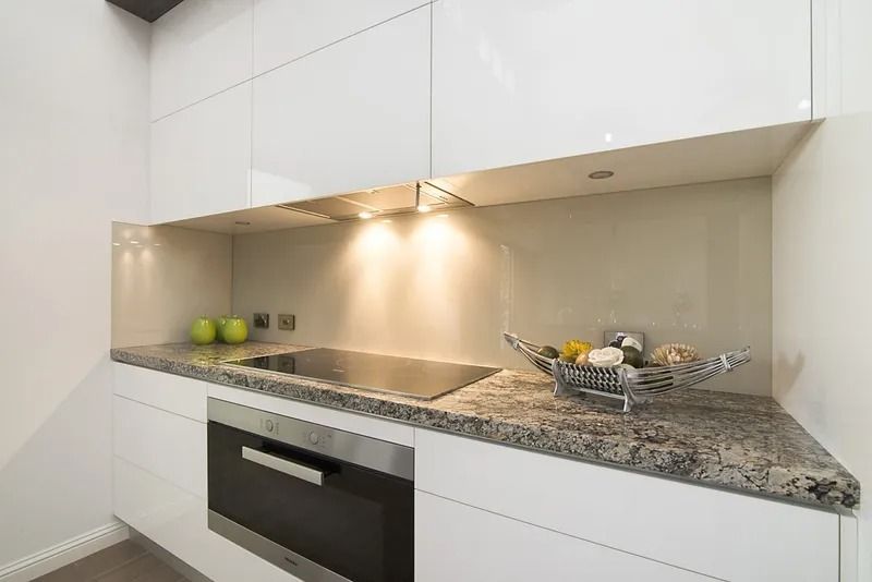 A kitchen with white cabinets , granite counter tops , stainless steel appliances and a bowl of fruit on the counter — Precision Shower Screens & Wardrobes In Yarrawonga, NT