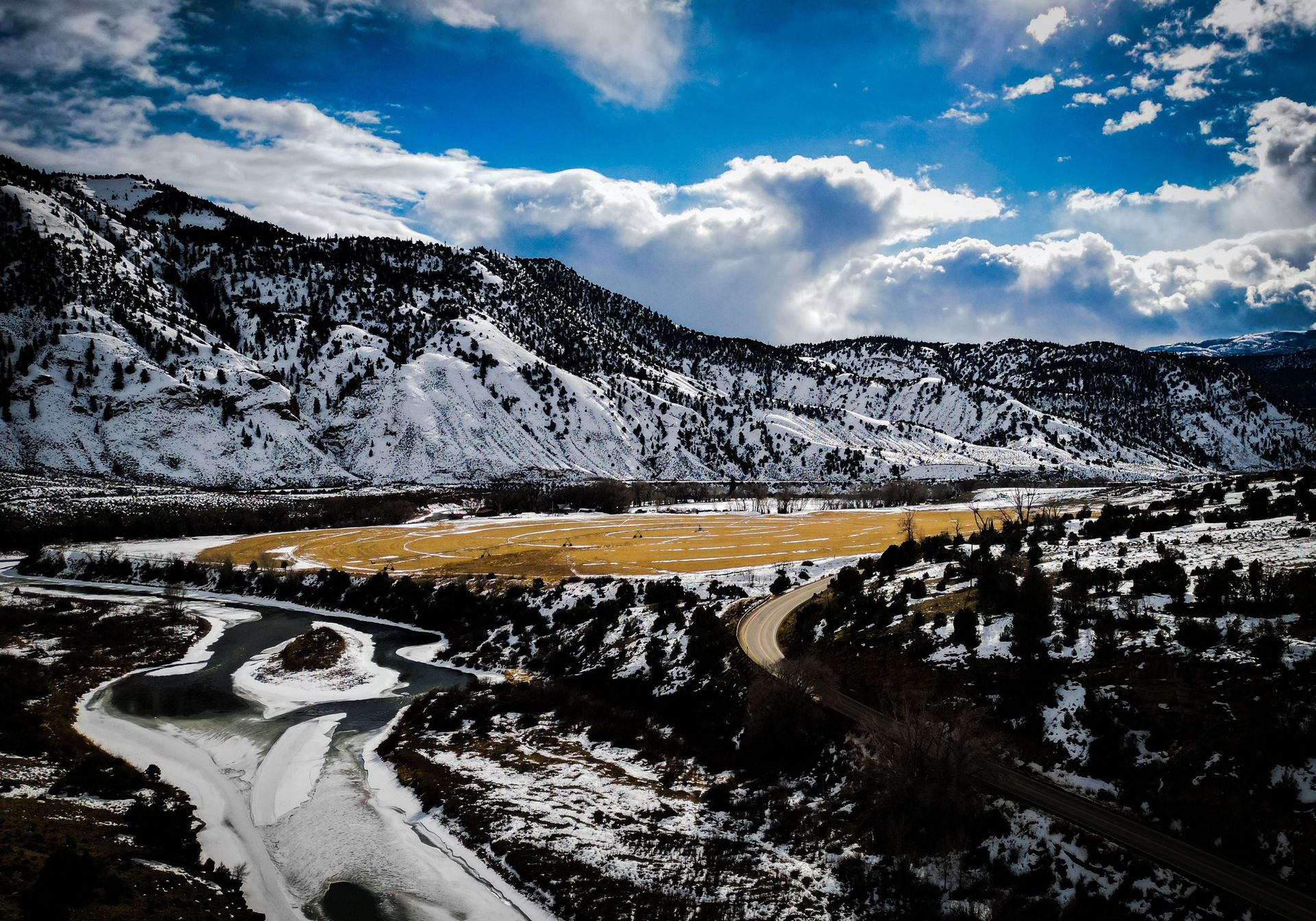 An aerial view of a snowy mountain range with a river running through it