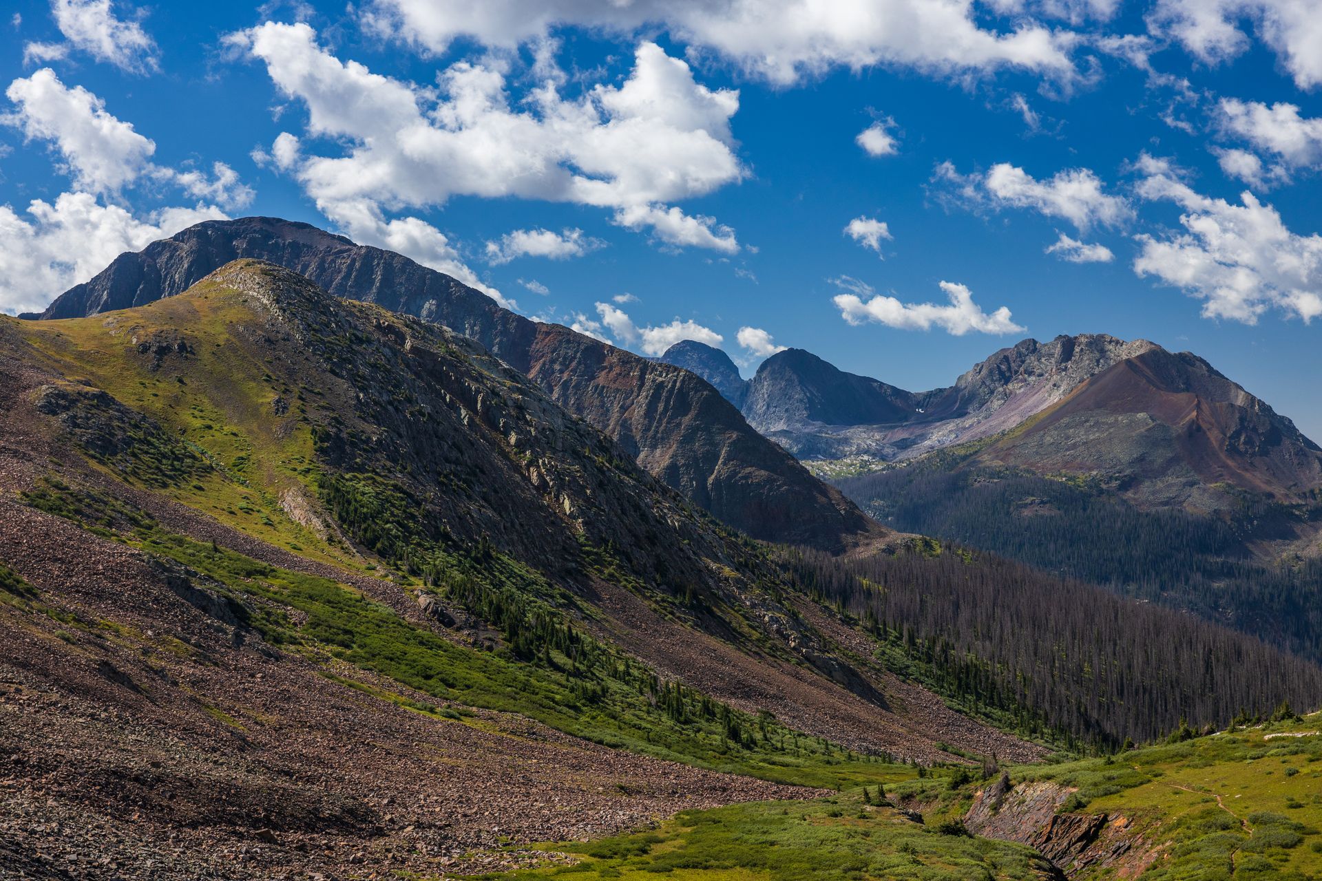 A mountain range with a blue sky and clouds in the background