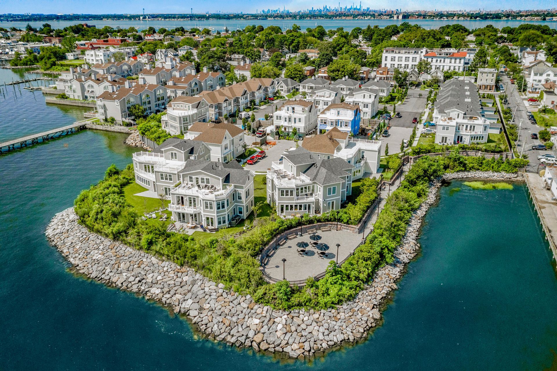 An aerial view of a small island in the middle of a body of water surrounded by houses.