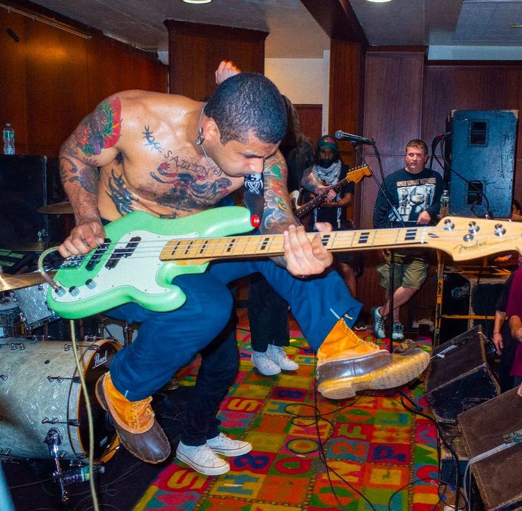 A shirtless man is playing a green guitar