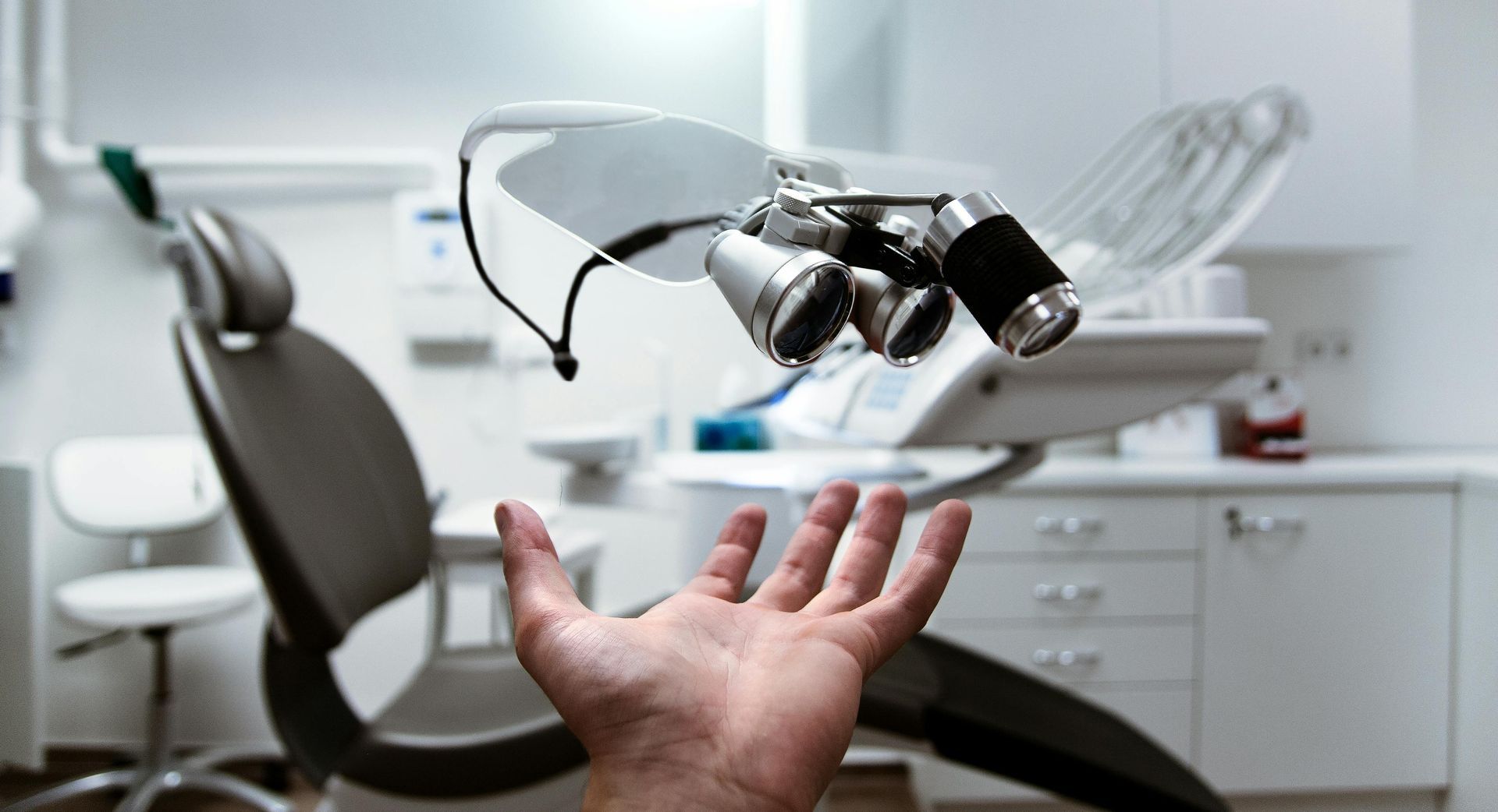 Hand reaching up toward dental equipment in a bright, white office.