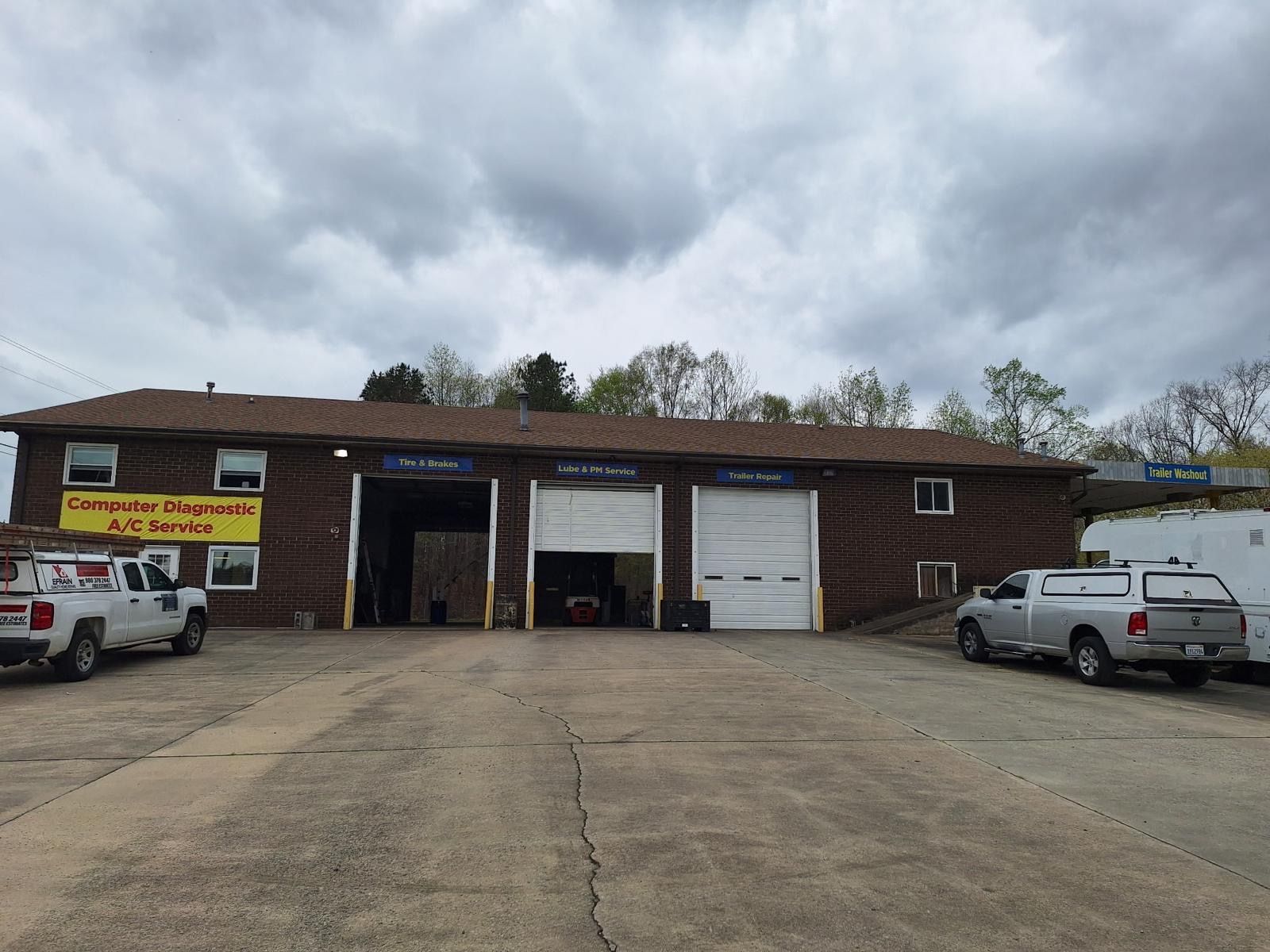 Auto repair garage with open bays and parked pickup trucks in front