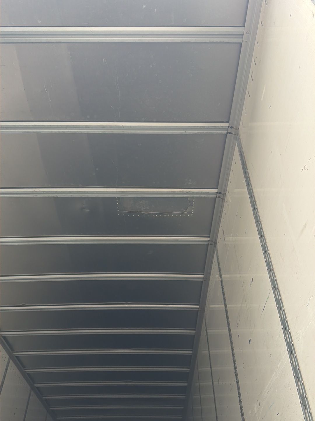 Underside of a gray metal staircase or catwalk beside a white cinderblock wall