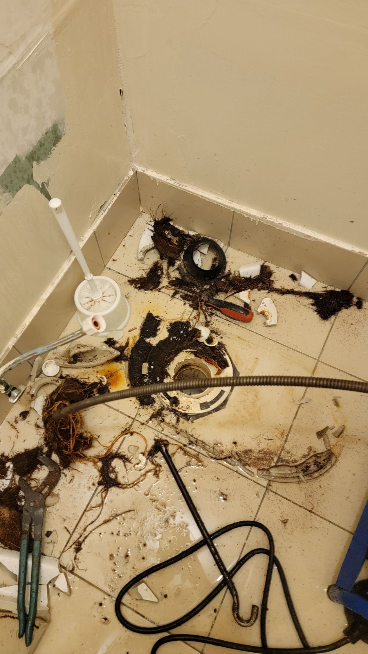 Messy floor corner with spilled debris, tangled cords, and a white lamp base against beige walls