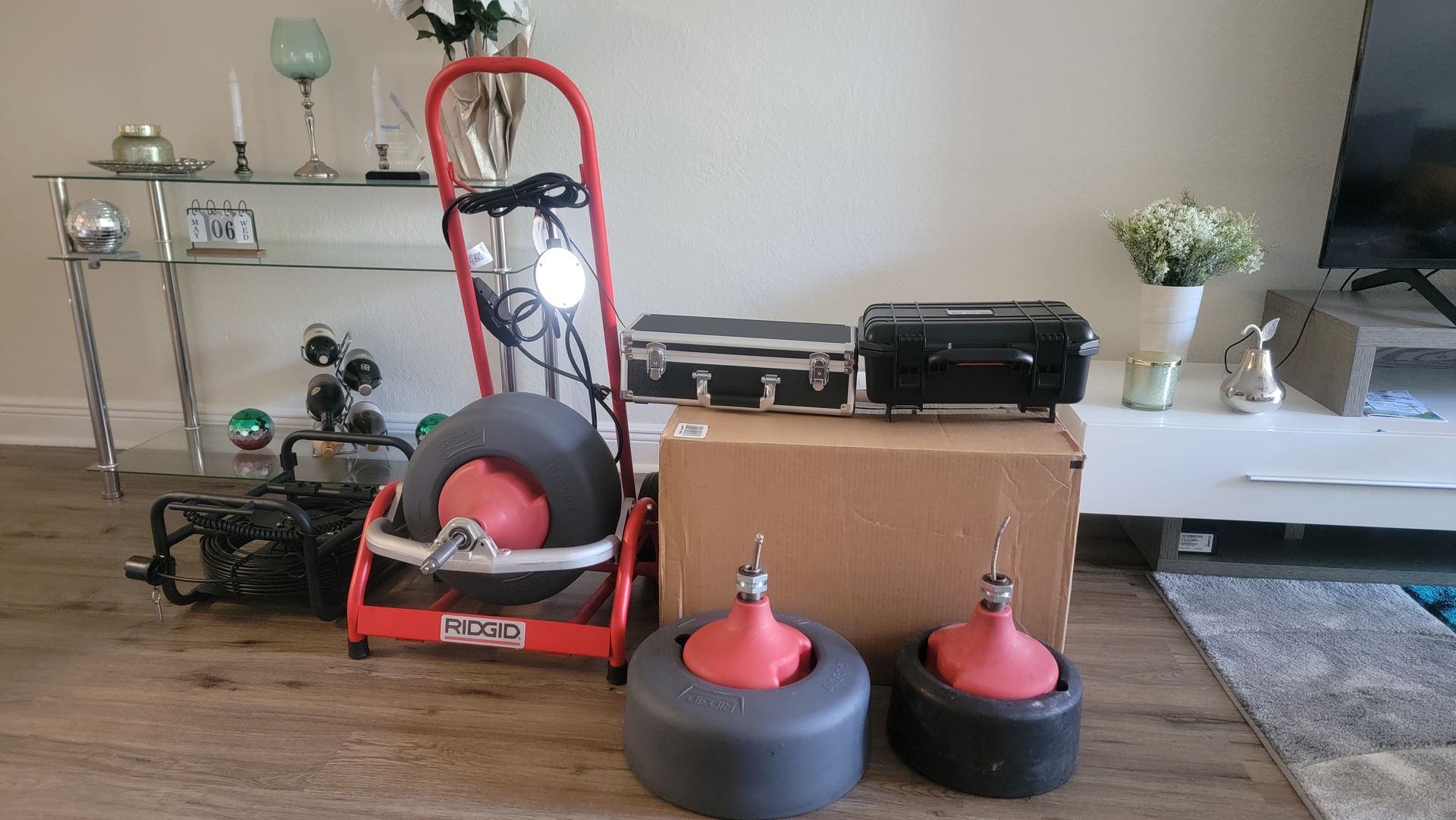 Living room with cleaning equipment, boxes, and two black-and-red floor buffers on the floor