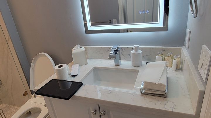 Bathroom vanity with double sinks, mirror, towel, and toiletries on a white countertop.