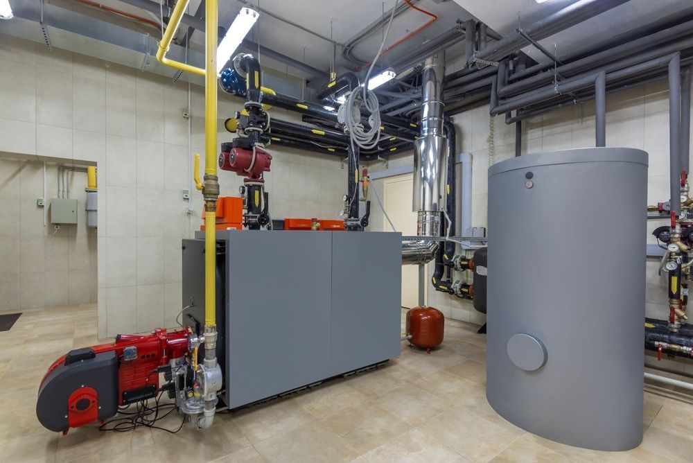 Industrial mechanical room with gray equipment, red pump, overhead piping, and a large cylindrical tank