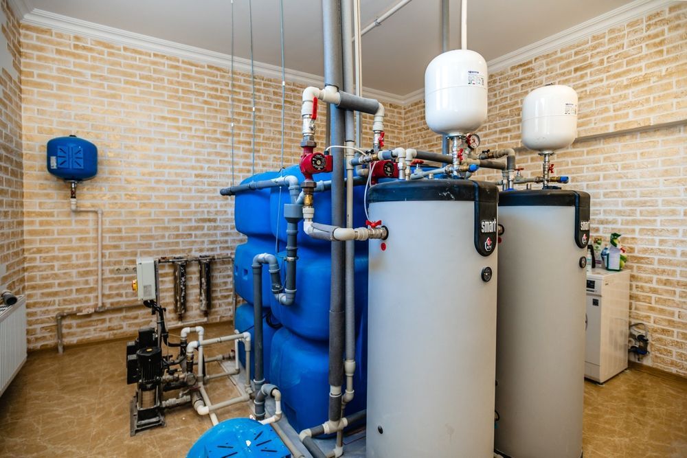Industrial water treatment equipment with blue and white tanks and pipes in a utility room