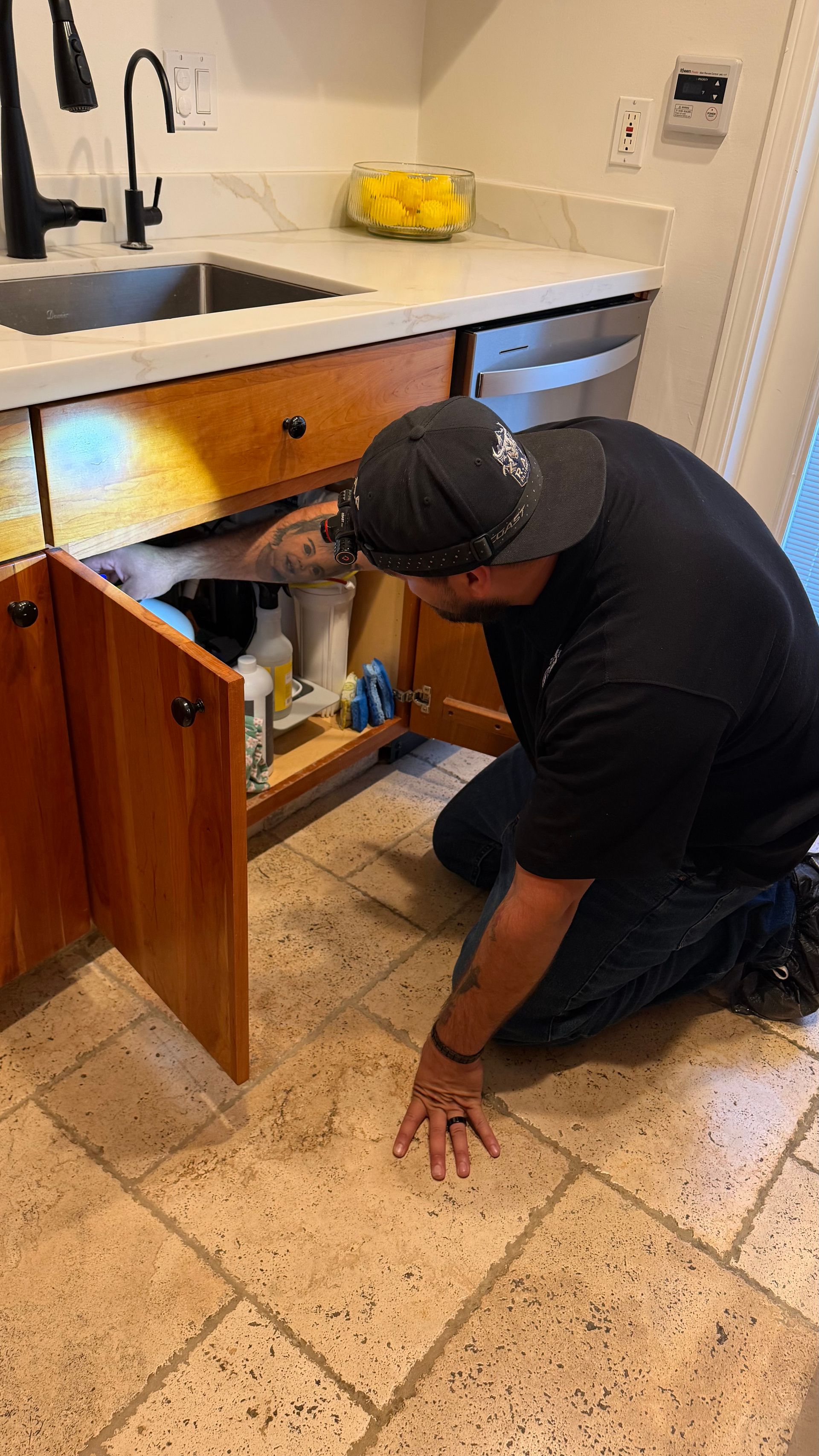 Gloved hand tightening a chrome sink pipe under a bathroom faucet