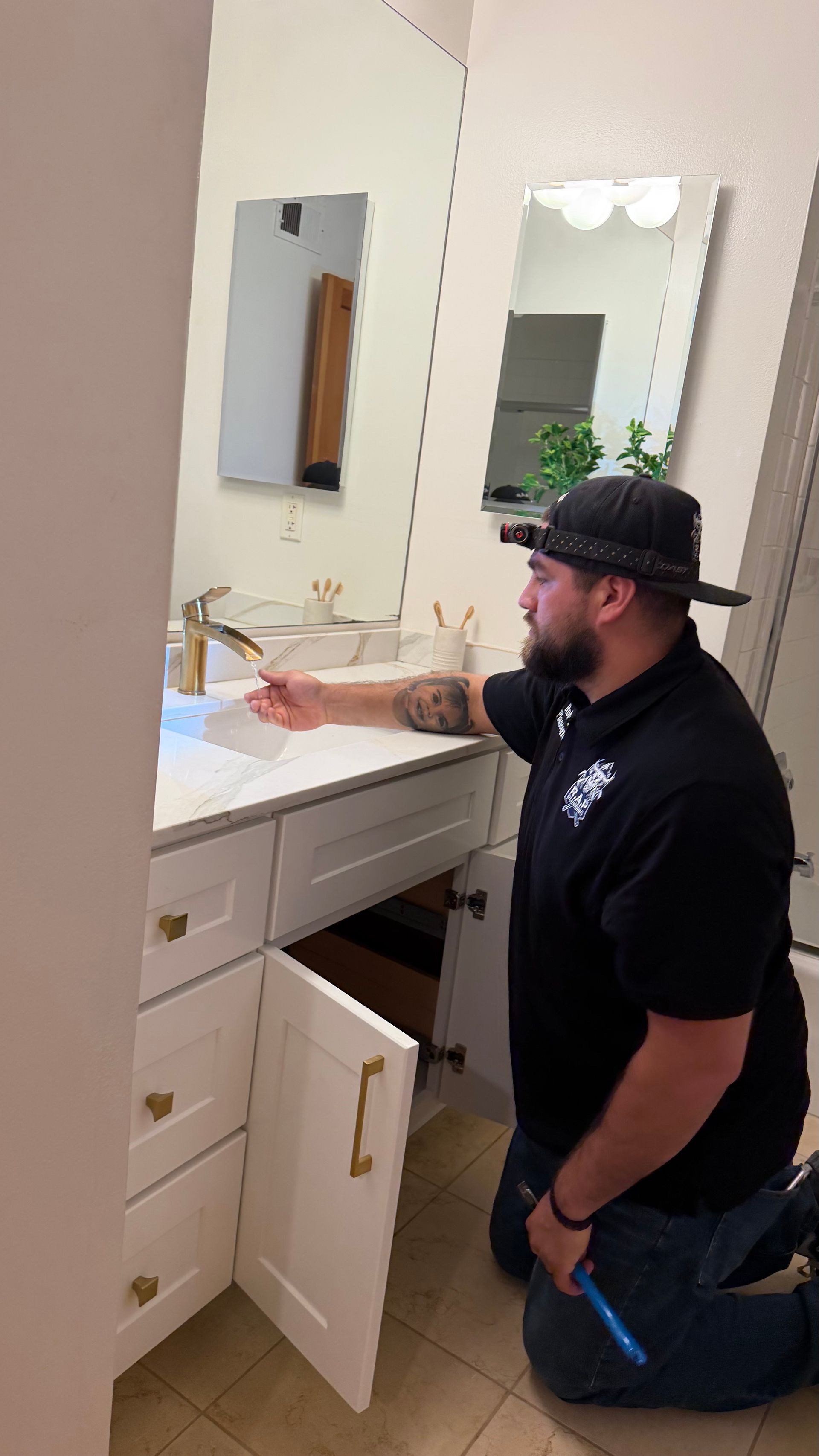 Hands holding braided hoses and a wrench while adjusting a plumbing valve.